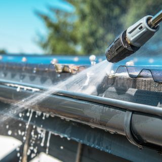 Spring Rain Gutters Cleaning Using Pressure Washer. Closeup Photo.