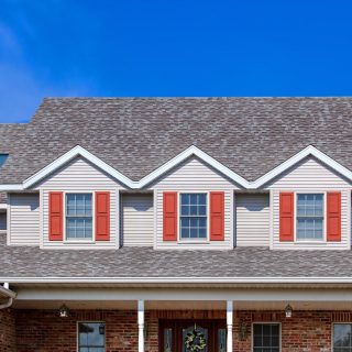 "New two story home showing vinyl siding, roof, gutters with blue sky in the background."