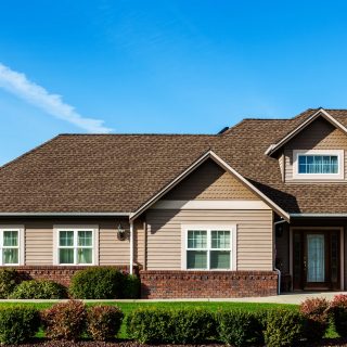 Partial image of a modern American home with focus on roof detail against blue sky.